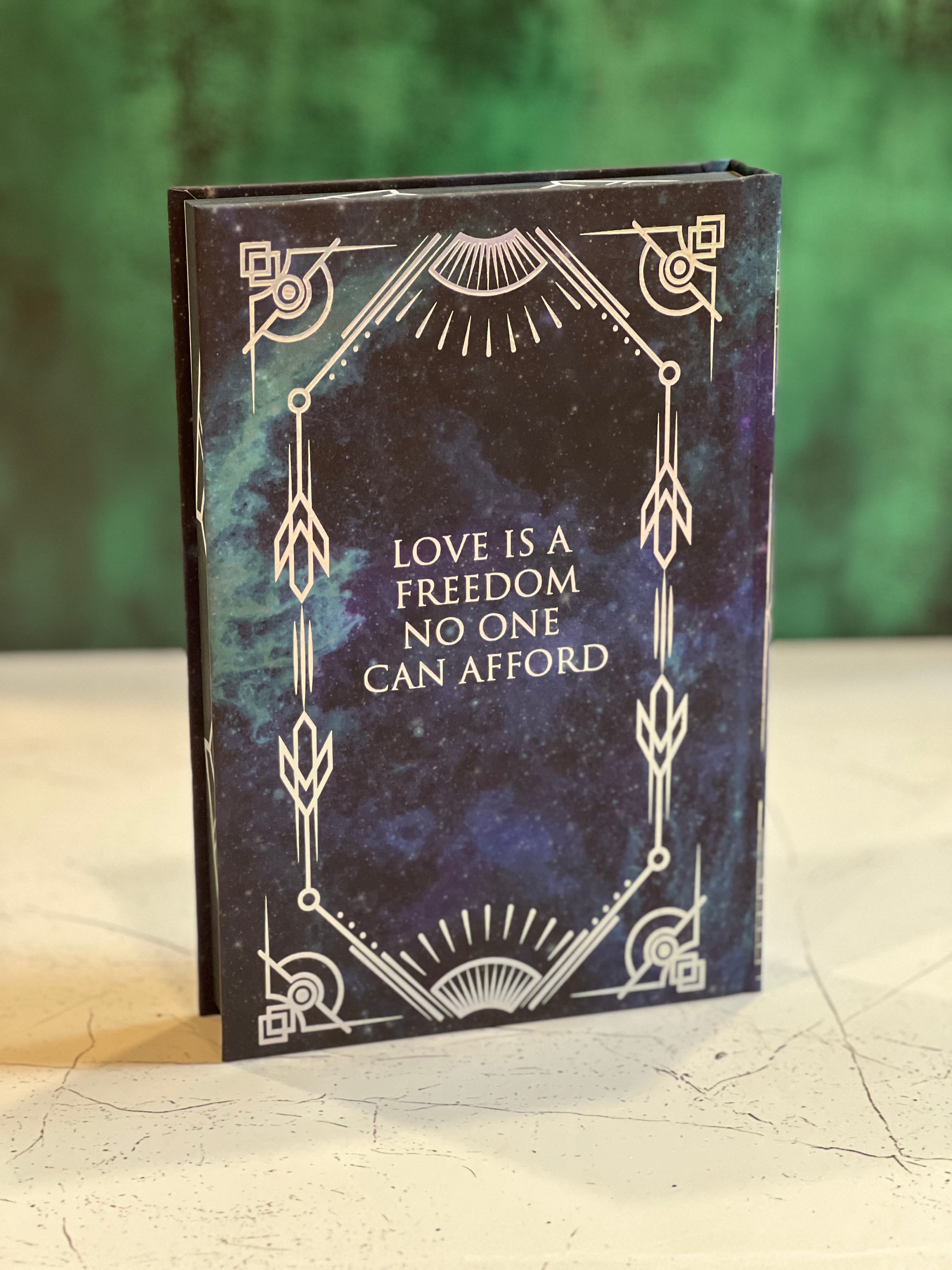 Book with decorative cover and text 'Love is a freedom no one can afford' on a textured surface.